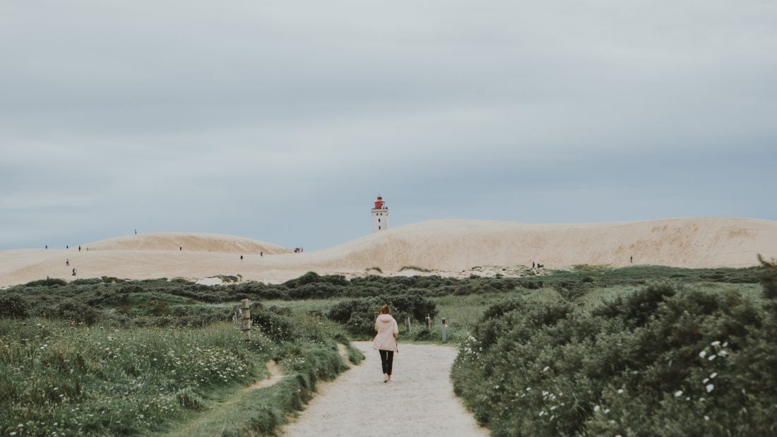 Girl walking towards the sand dunes of Rubjerg Knude in Lokken