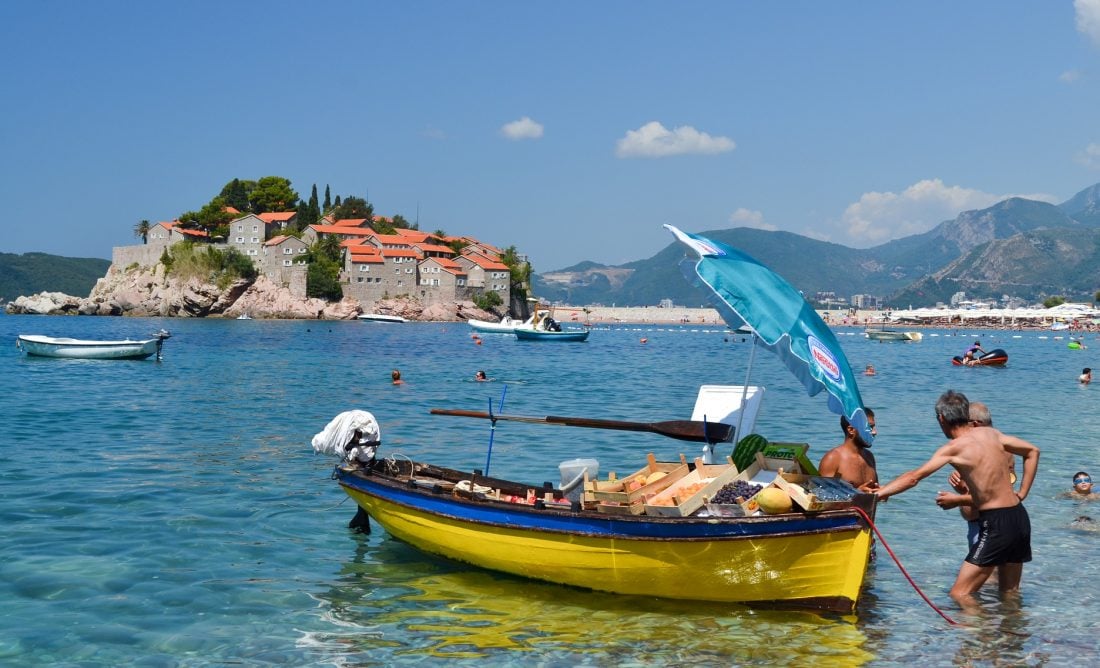 Man standing by a boat on the shore of Zlatni Rat in Brac Montenegro