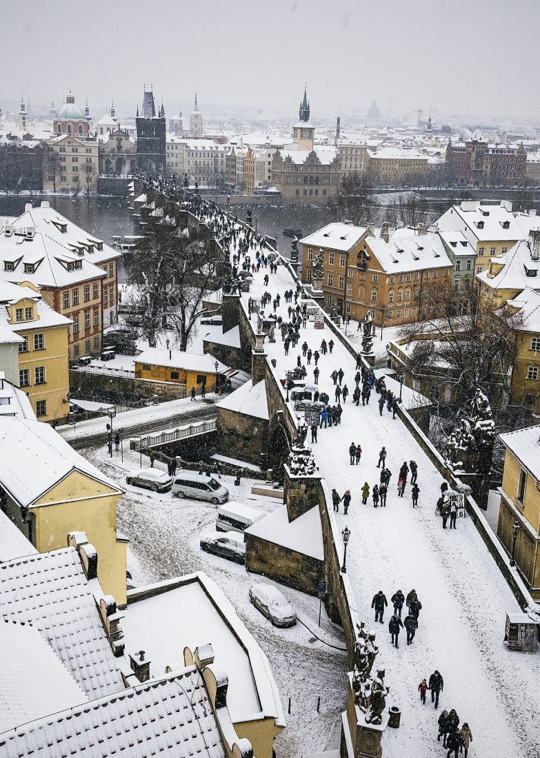 the charles bridge during snowfall in Prague