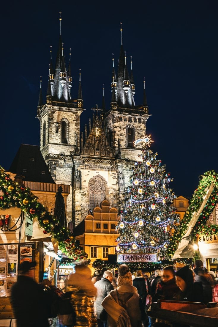 People standing under the Christmas tree and talking in Prague's Old Town Square Christmas Market