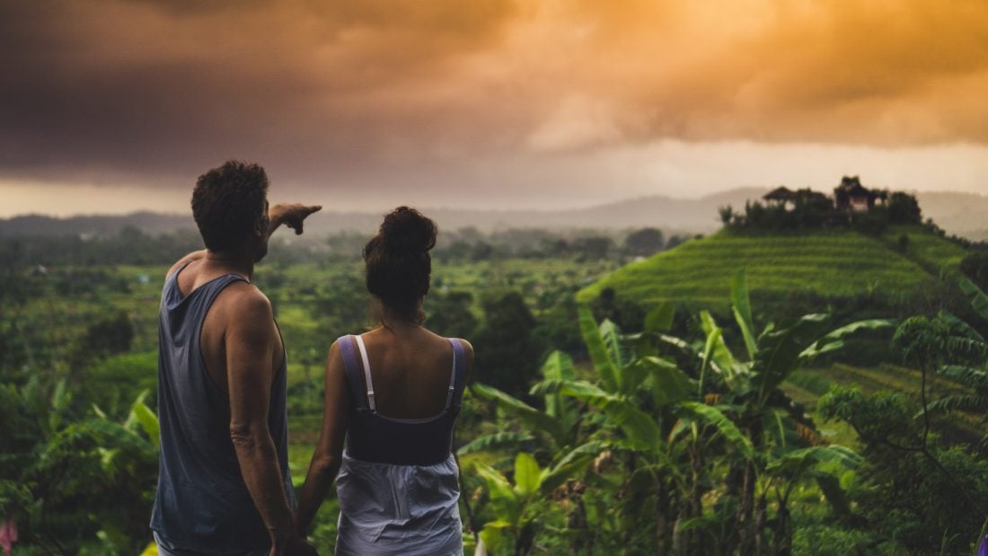man and woman looking ove rlush green fields during a sunset in Bali, Indonesia