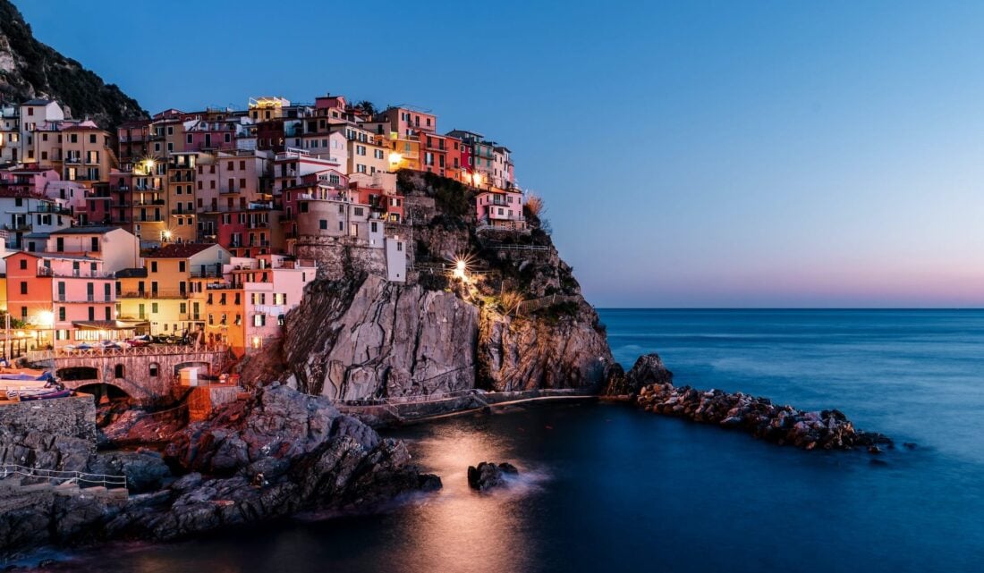 Colorful houses perche don a hill during sunset in Cinque Terre, Manarola, Italy