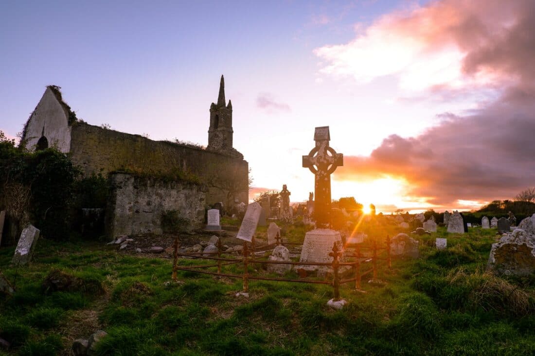 sunset over a cemetery and church in cork ireland