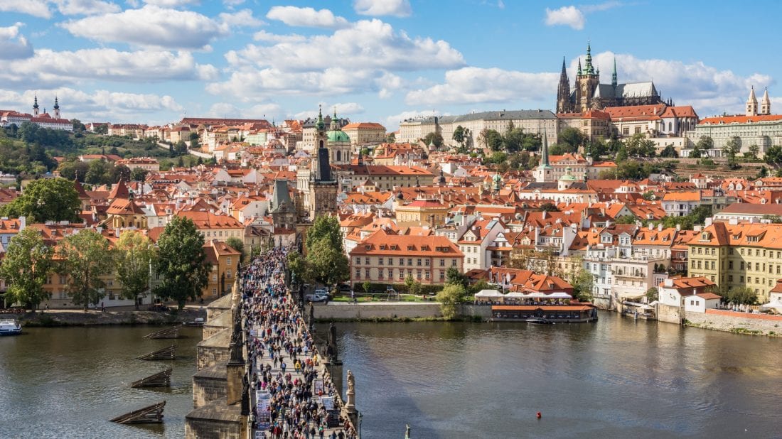 the rooftops of Prague and Prague Castle as seen from the Tower Bridge over the Charles Bridge