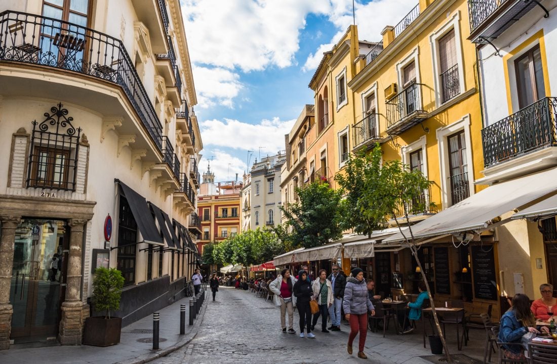 People walking down a street with outdoor dining options in Sevilla, Spain