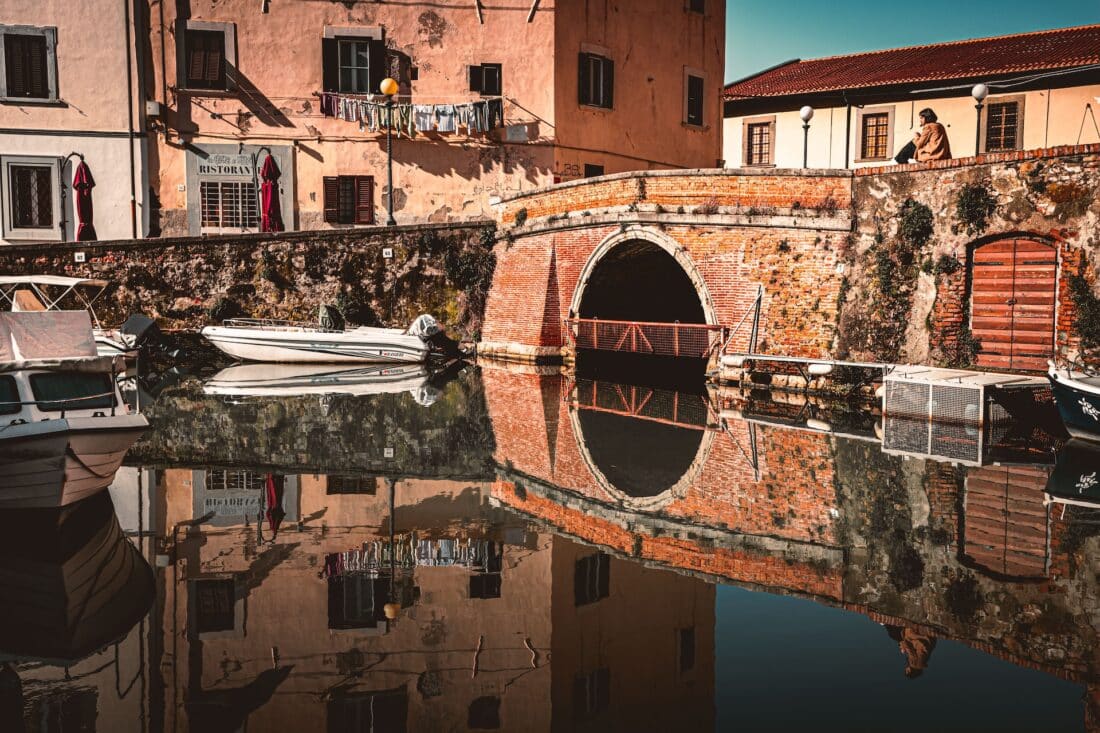 Girl sitting on a stone bridge in Livorno, Italy.