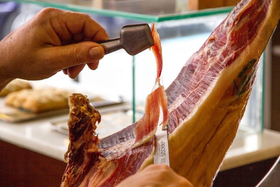 Man slicing off a thin strip of jamon iberico in Barcelona Spain