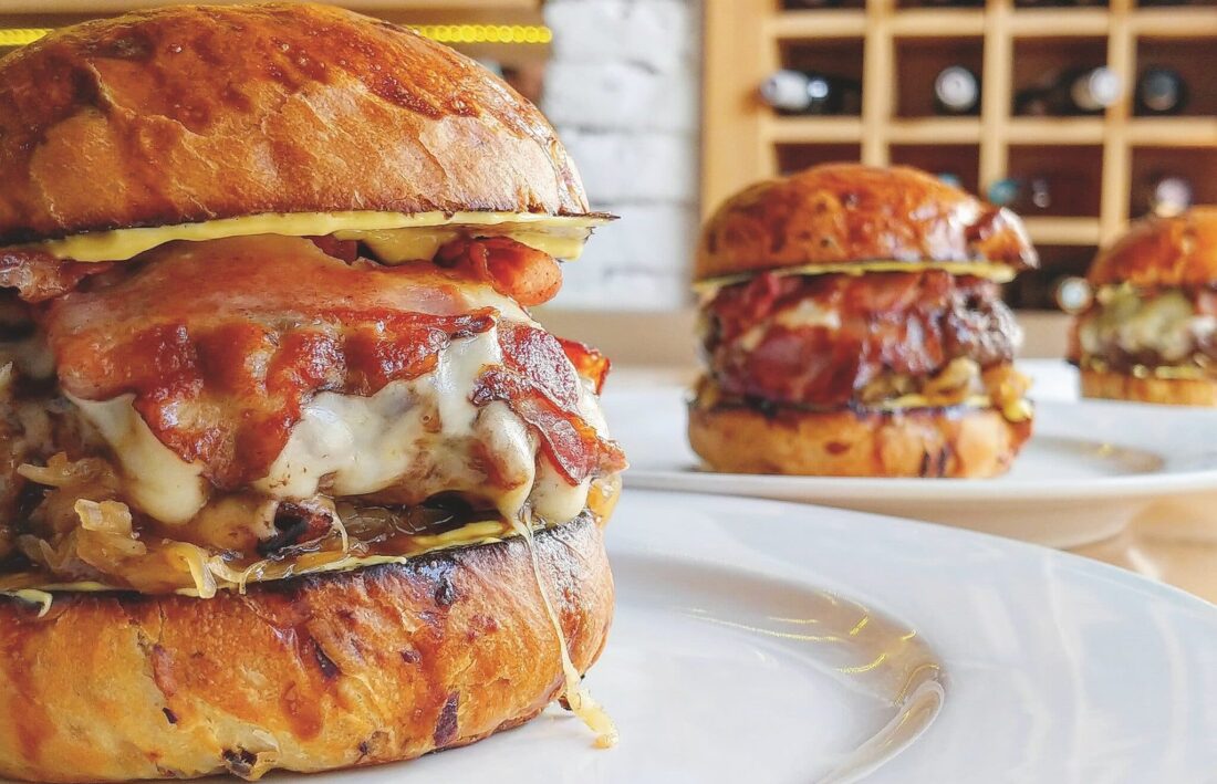 Three bacon cheeseburgers lined up in a row on a table