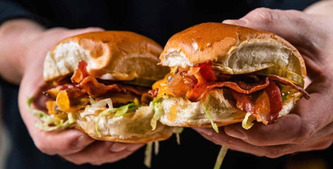 man holding two burgers in his hands