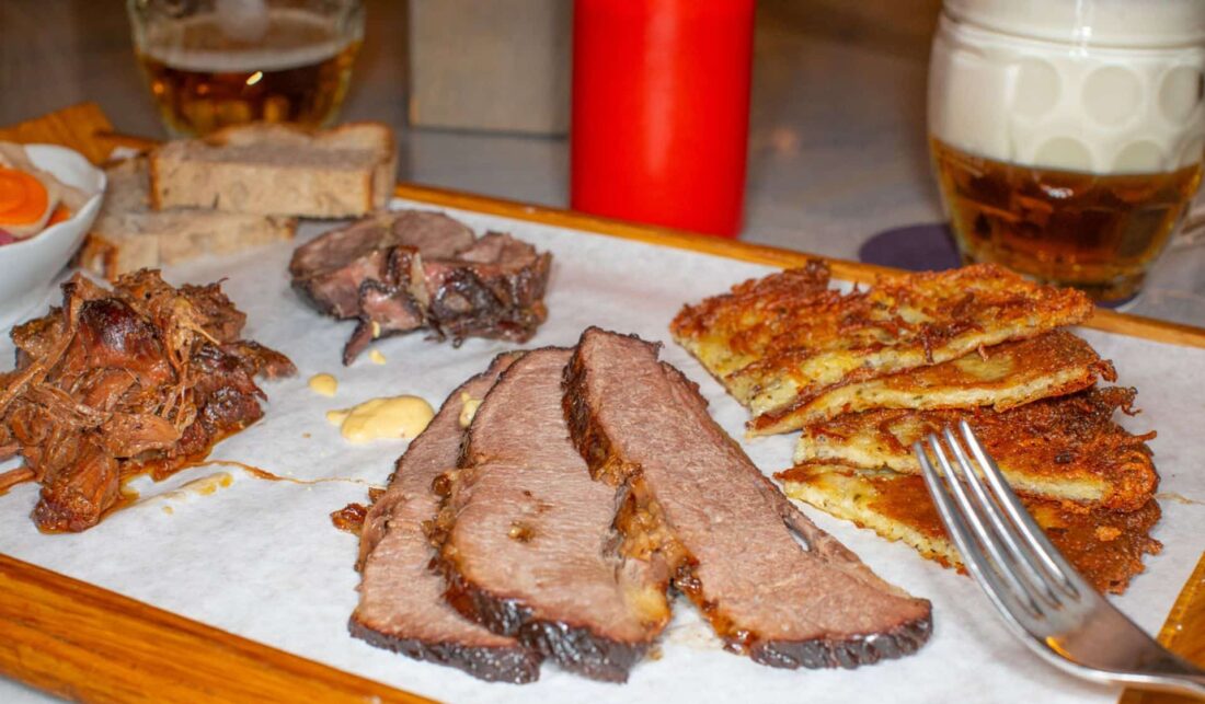 Various roasted meats on a large plate with beer in Prague