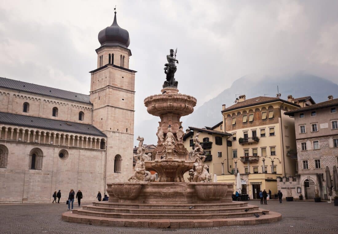 Fountain and church in Trento Italy's town square.