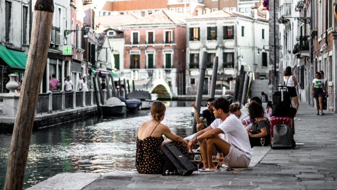 People sitting by a canal in Venice, Italy.