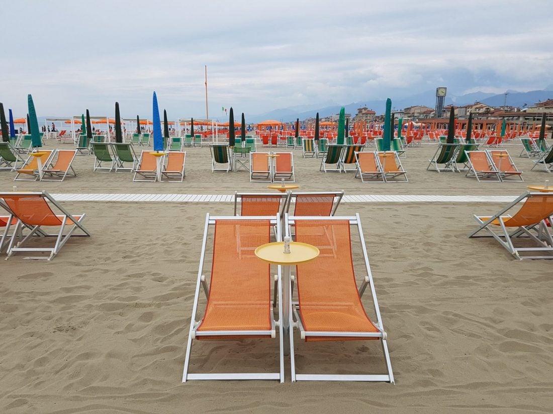 Beach chairs in the sand on the coast of Viareggio Italy.